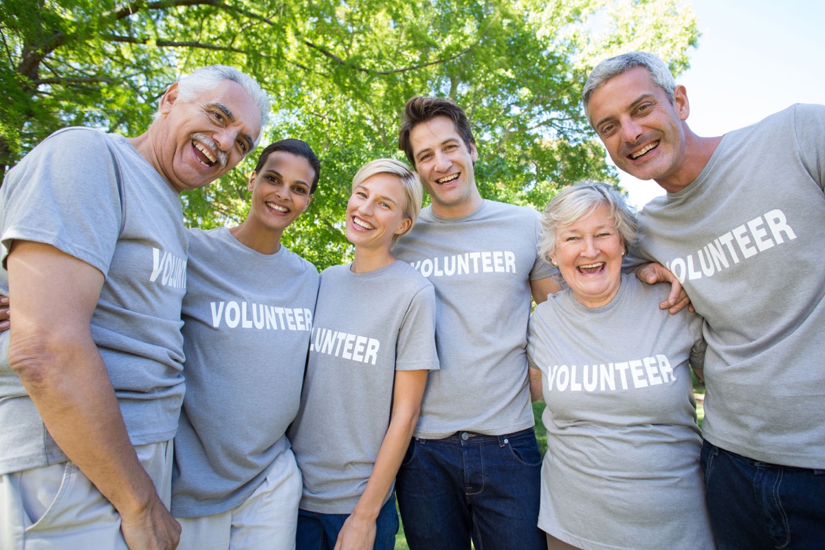 Happy volunteer family smiling at the camera on a sunny day; community engagement concept