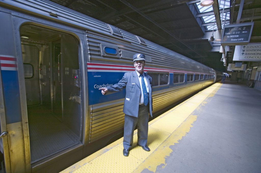 conductor at amtrak train platform announces ""all aboard"" at east coast train station on the way to new york city, new york, manhattan, new york