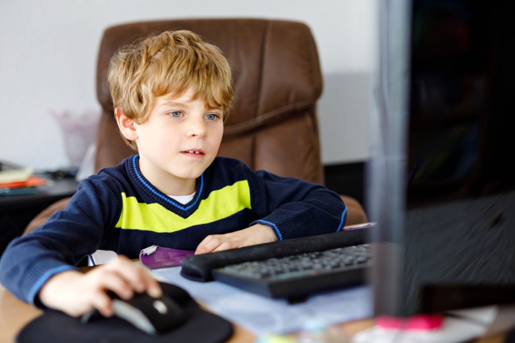 Little kid boy making school homework on computer notebook. Happy healthy child searching information on internet. New media education, kid watching learning lessons on pc. Virtual classroom