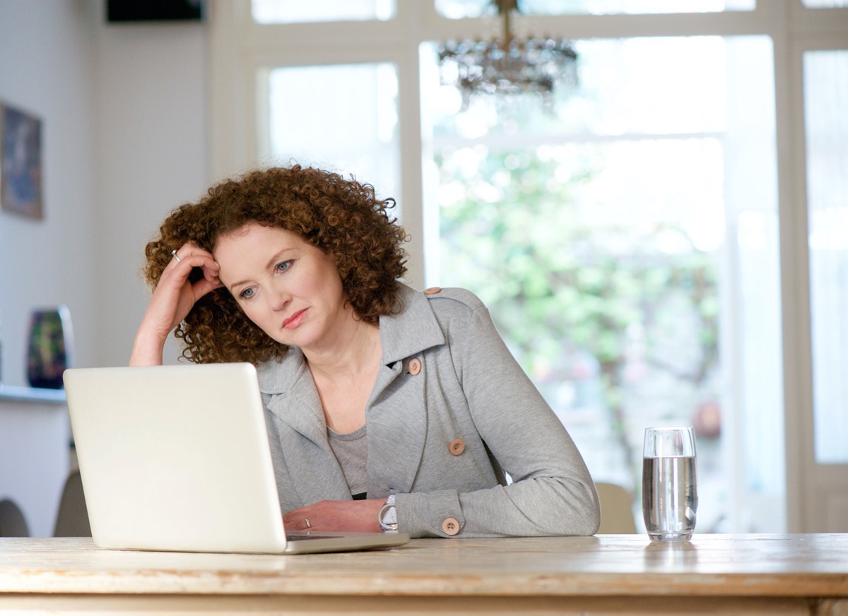 portrait of an older woman looking at laptop at home; remote work challenges concept