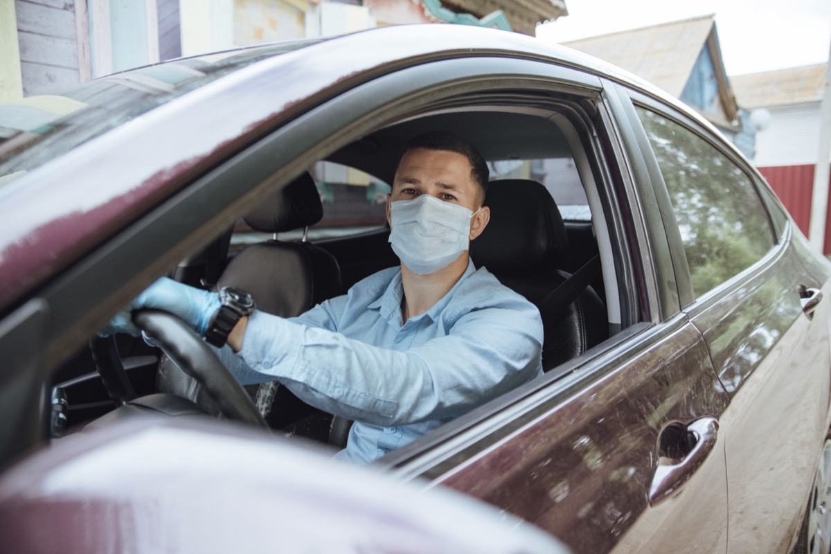 A man driving a rideshare car in a protective mask and gloves; organize gig workers concept