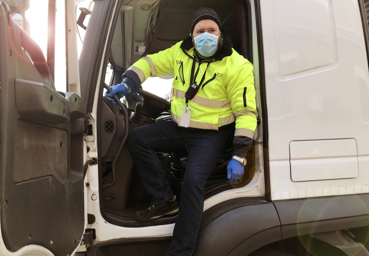 young transporter on the truck with face mask and protective gloves; unions protect workers during Covid-19 concept.
