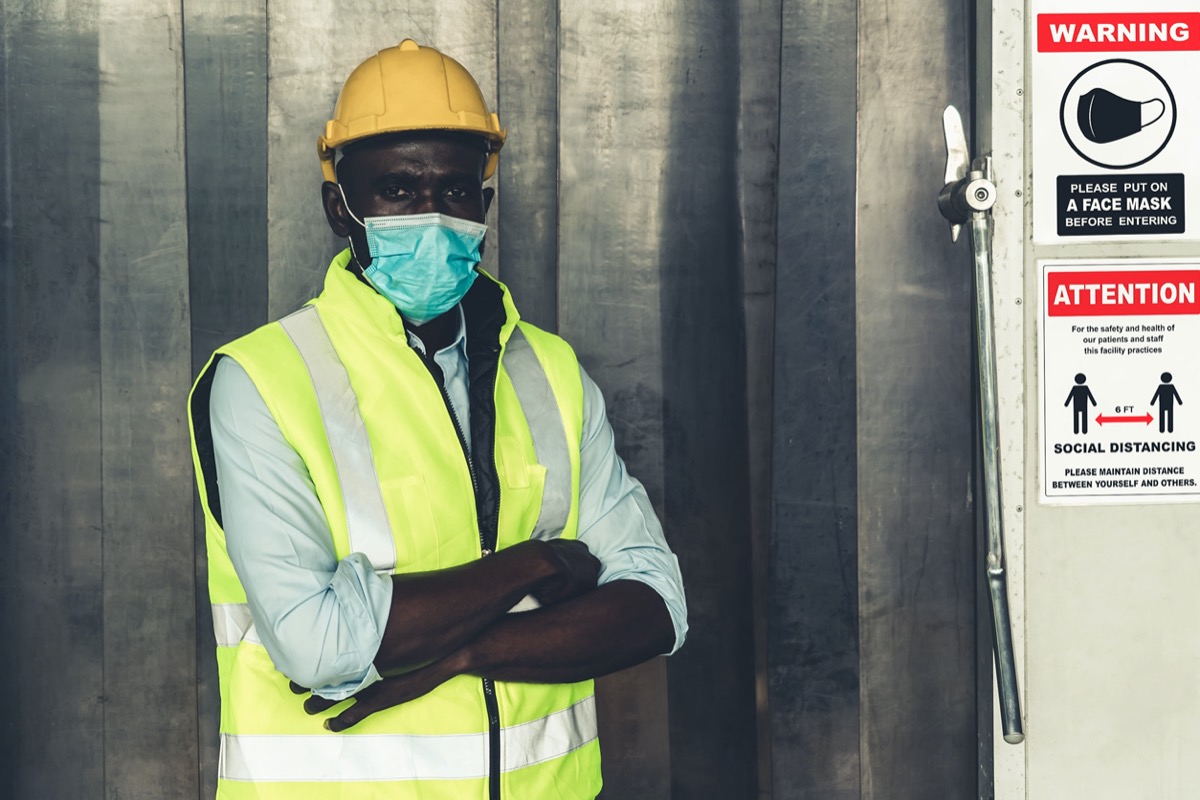 Caution sign in factory warning to industry labor worker to prevent Covid-19 Coronavirus spreading. Automotive workers and COVID concept.