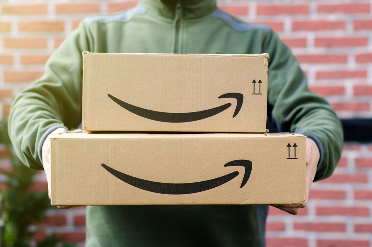 Man delivers Amazon package; concept: how 2020 online holiday shopping resulted in worker exploitation