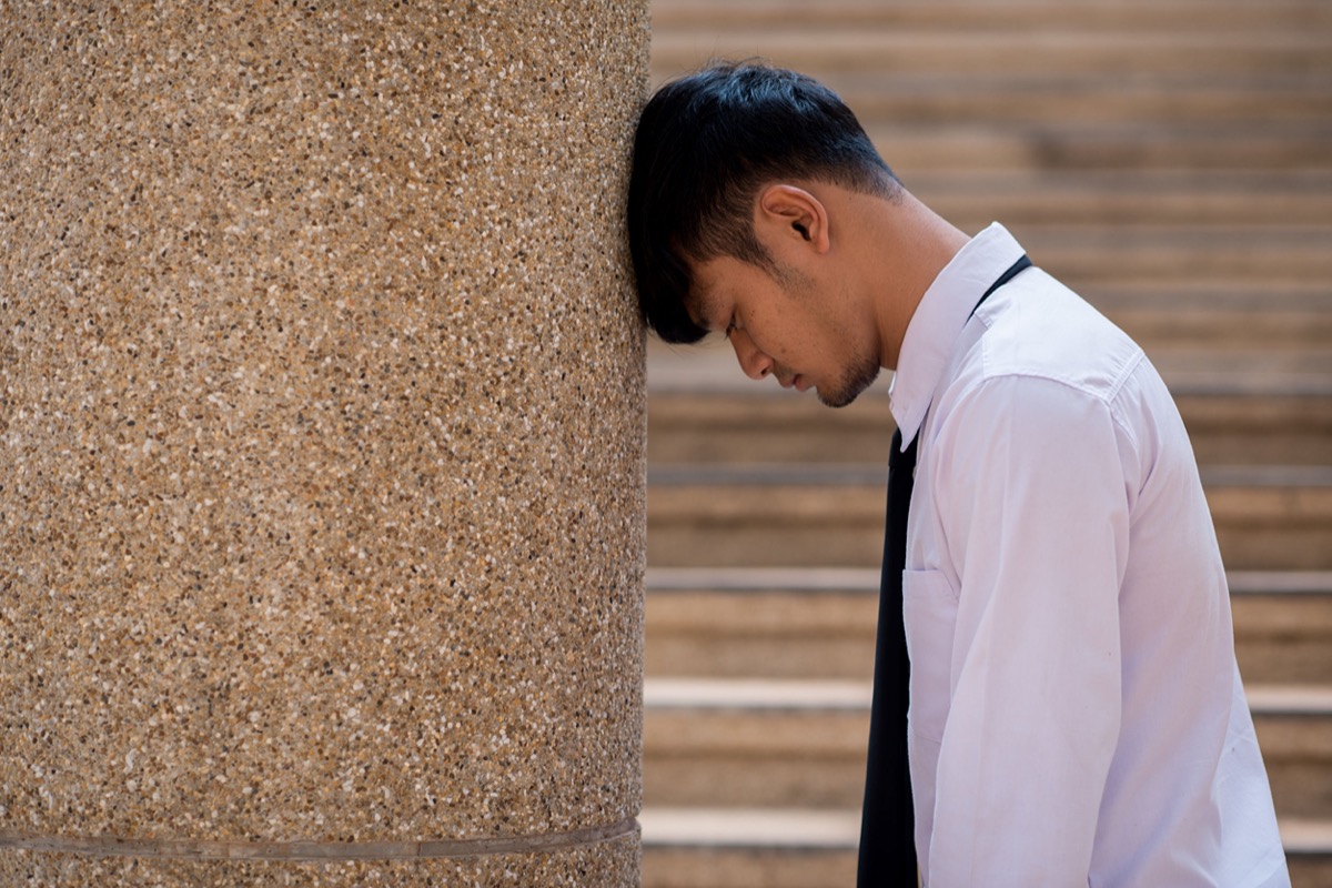 frustrated worker leans against wall; covid unions and mental health concept