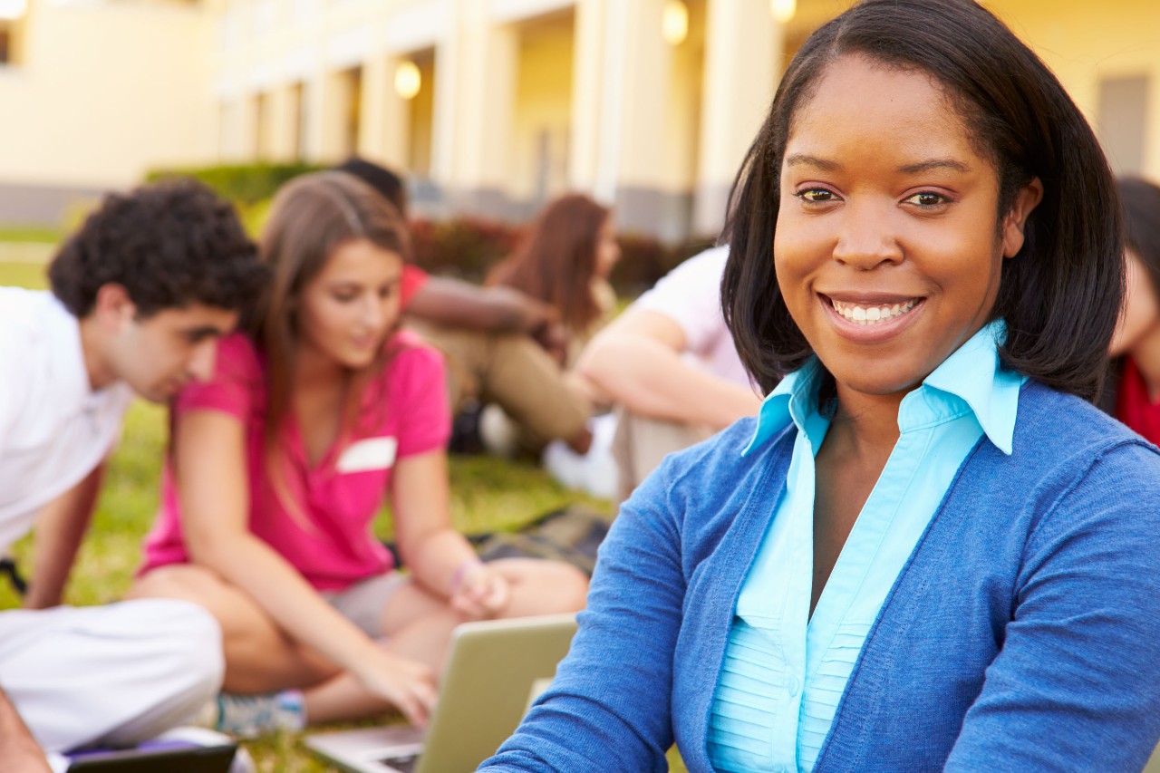 smiling teacher in front of students studying outside; Randi Weingarten advocates for educators concept