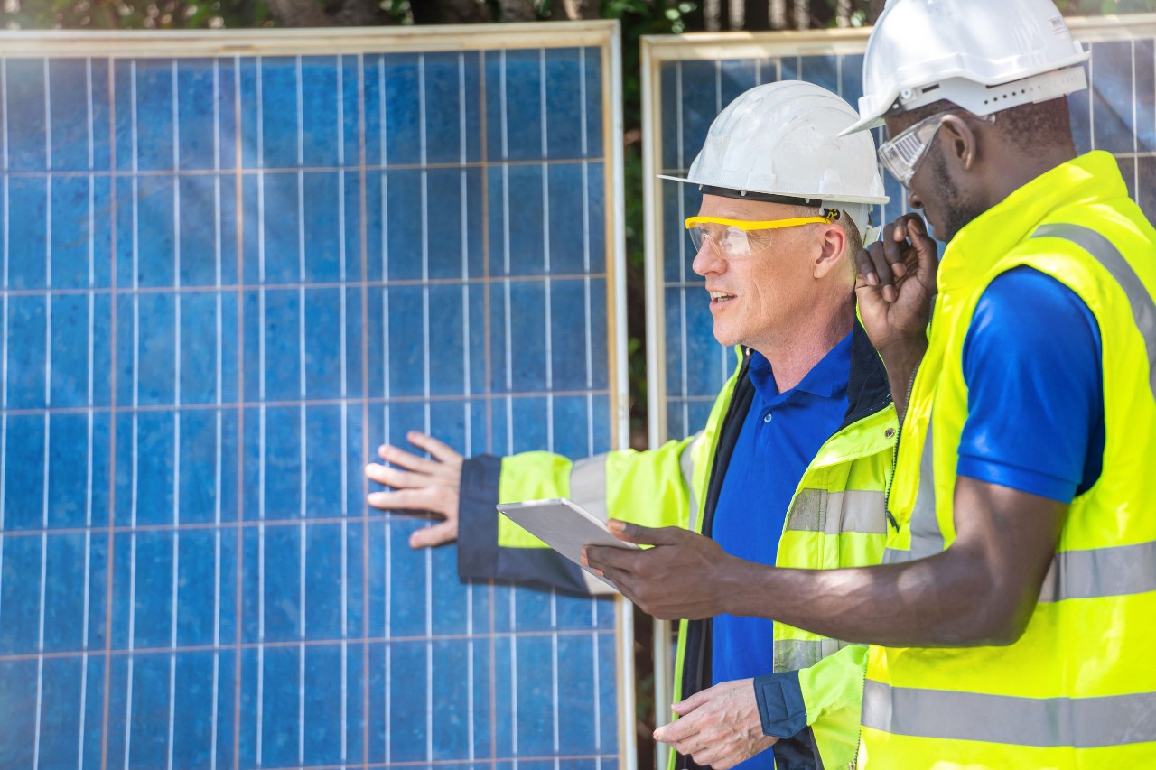 two construction workers talk near solar panels; American jobs plan and labor interests concept
