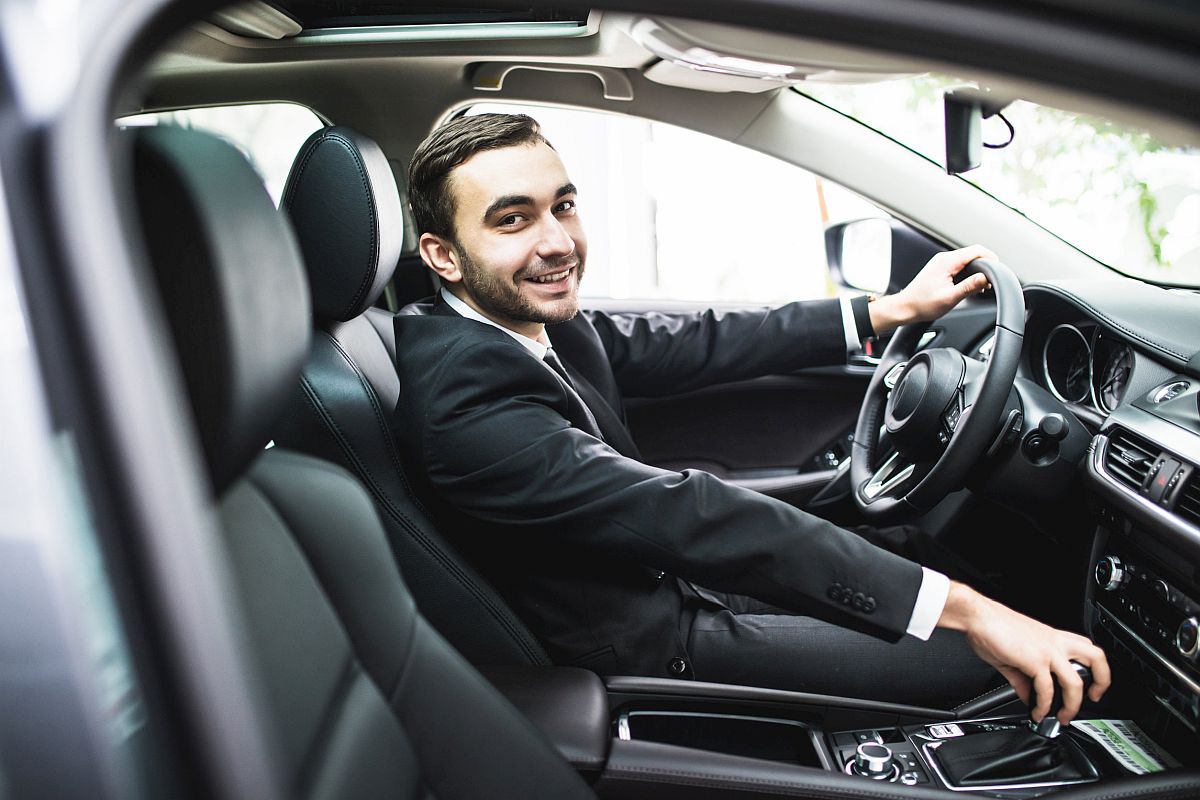 gig workers concept - close up of young man in suit driving car