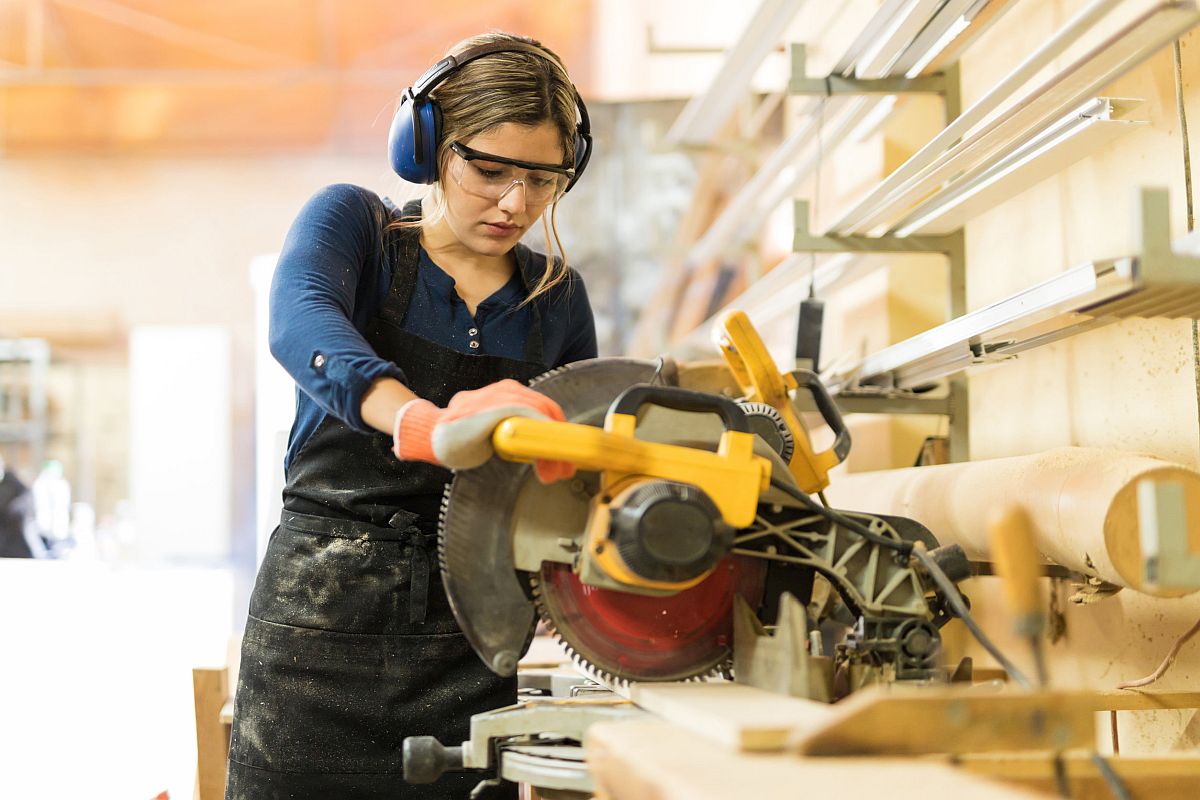 Female carpenter using a circular saw in a woodshop; unions gender equity concept