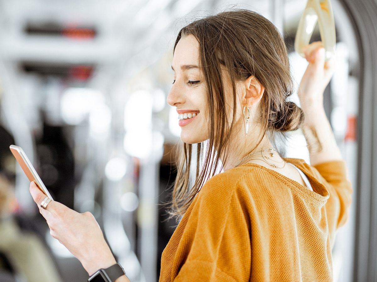 Close-up portrait of a young woman using smartphone while standing on the subway; union communications concept