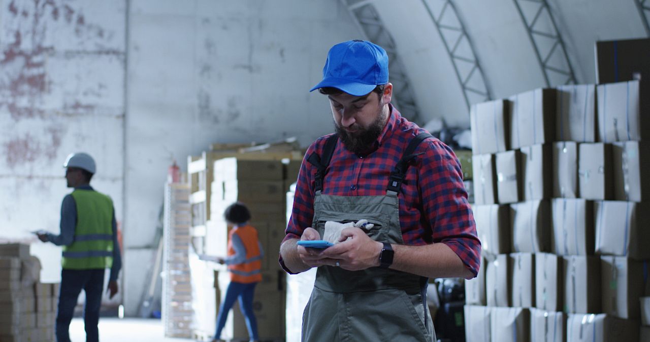 Medium shot of worker using phone in a warehouse; union communications concept